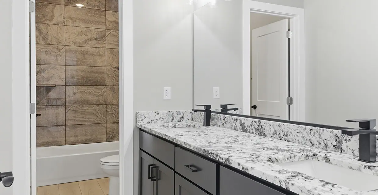 Westview Ridge upstairs bathroom with a double vanity, granite countertop, matte-black faucets and a tiled tub-shower