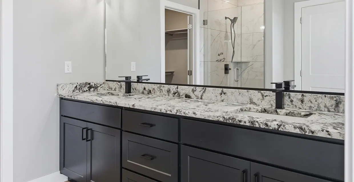 Westview Ridge primary bathroom with a black double vanity, granite countertop, frameless glass walk-in shower and walk-in closet