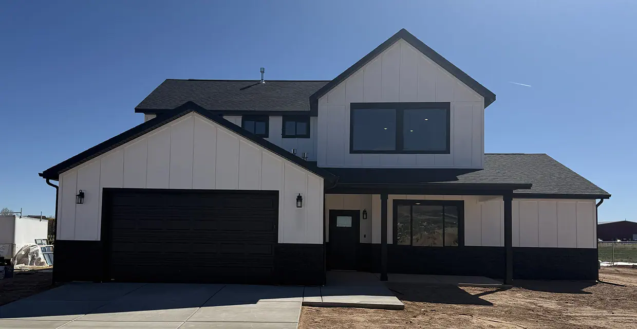 Real photo of a completed Westview Ridge new construction home in Cedar City, Utah, in the Alpine White exterior scheme with black trim and a covered front porch